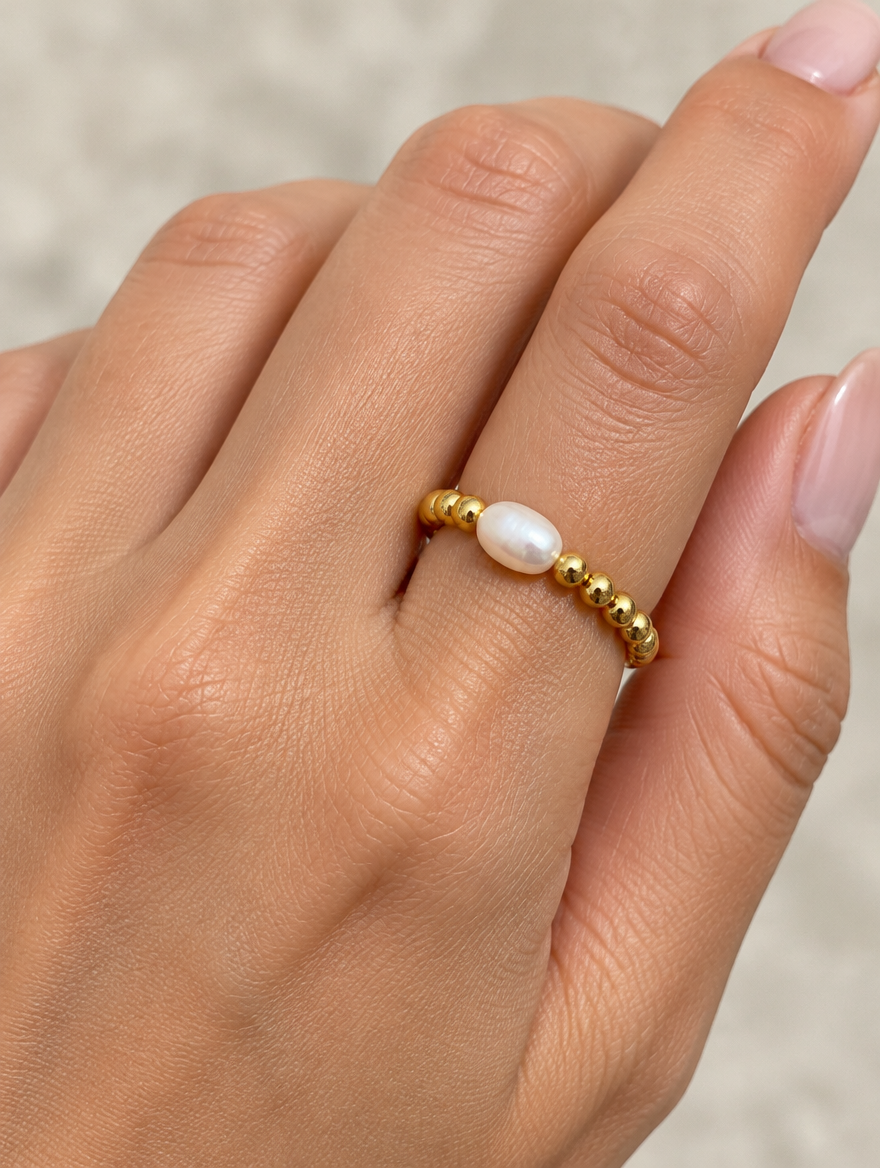Woman wearing a gold bead ring with a baroque pearl on her finger