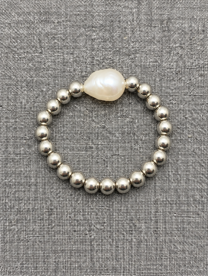 Silver bead ring with a baroque pearl resting on a soft textured surface