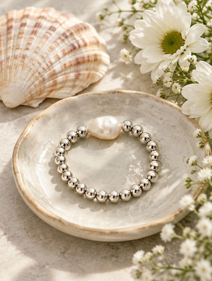 Silver bead ring with a baroque pearl in a small dish with styling props