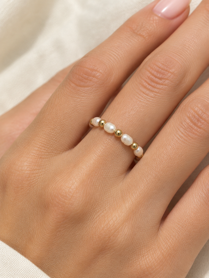 Woman wearing a gold bead ring with pearl accents on her finger