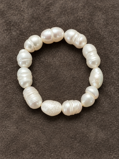 White baroque freshwater pearl beaded ring resting on a soft textured surface