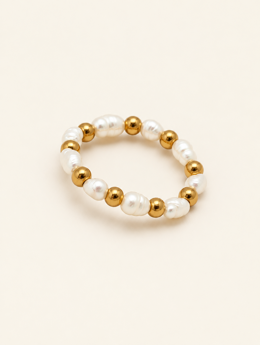 Gold bead ring with pearl accents on a neutral background