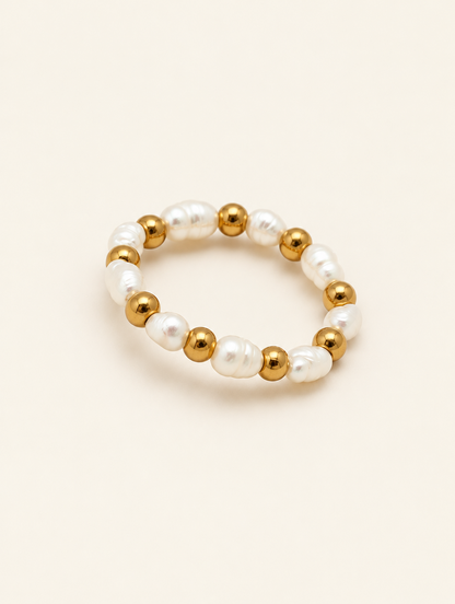 Gold bead ring with pearl accents on a neutral background