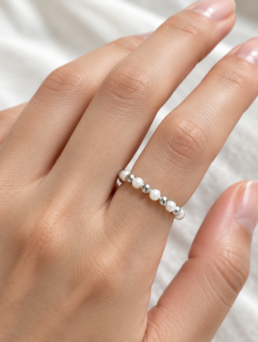 Woman wearing a silver mini bead ring with pearl accents on her finger