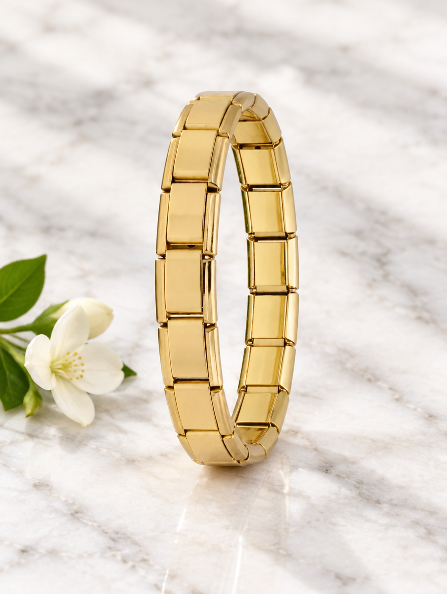 Gold-tone link bracelet beside a white flower on marble