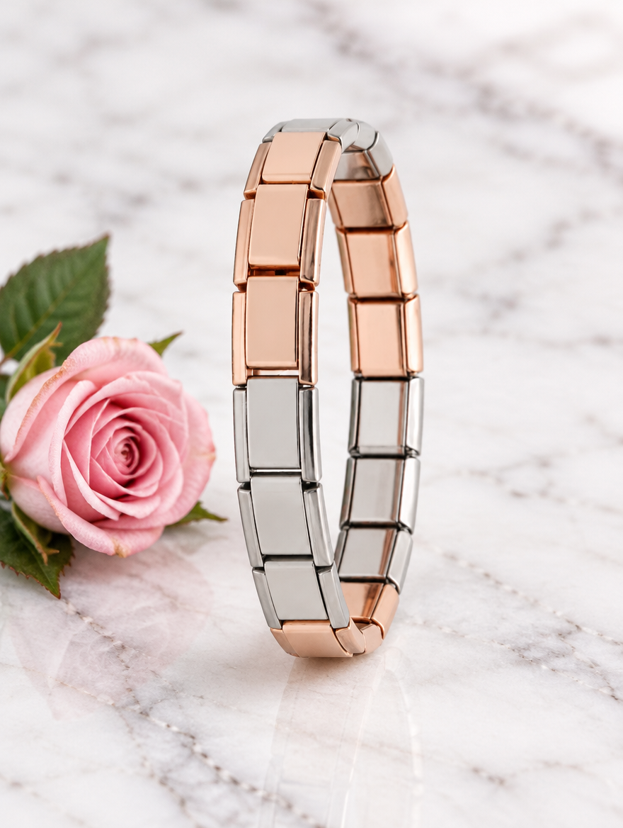 Rose gold and silver link bracelet beside a pink rose on marble