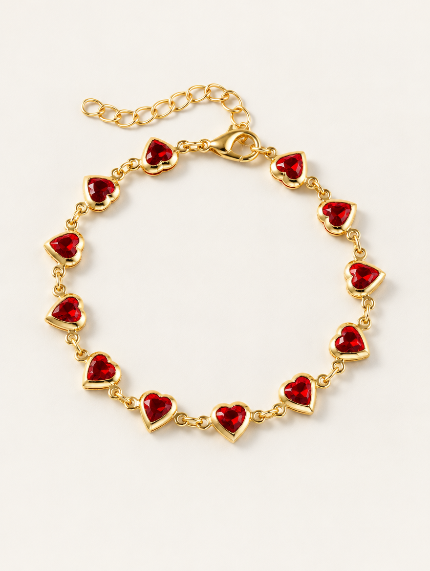 Gold-tone chain bracelet with red crystal hearts on a neutral background