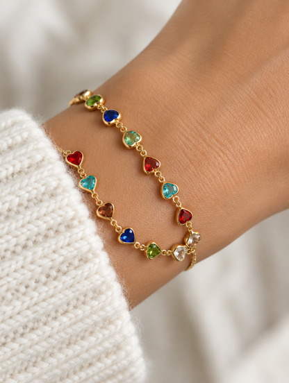Woman wearing a gold chain bracelet with multicolour crystal hearts