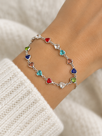 Woman wearing a silver chain bracelet with multicolour crystal hearts