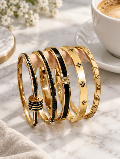 Black and gold bangles beside a coffee cup on marble