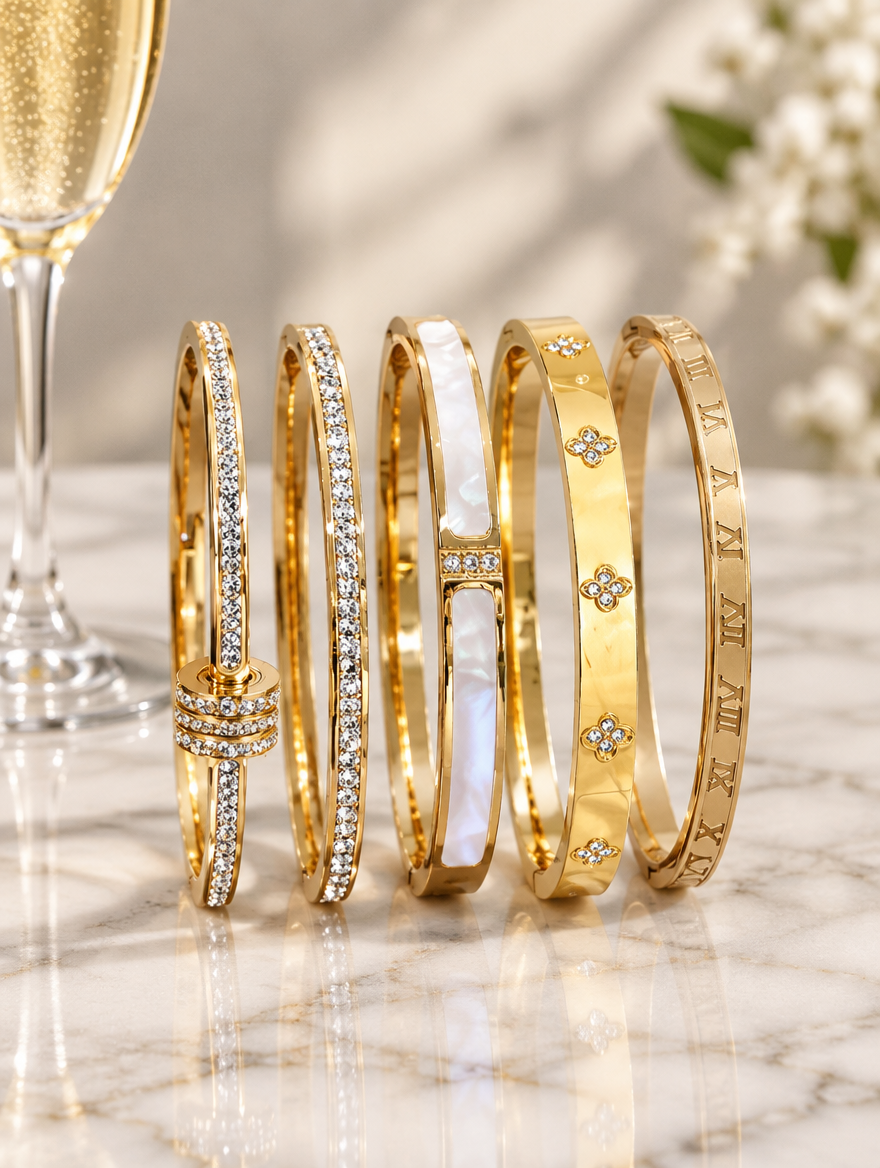 Five gold bangles beside a champagne flute on marble