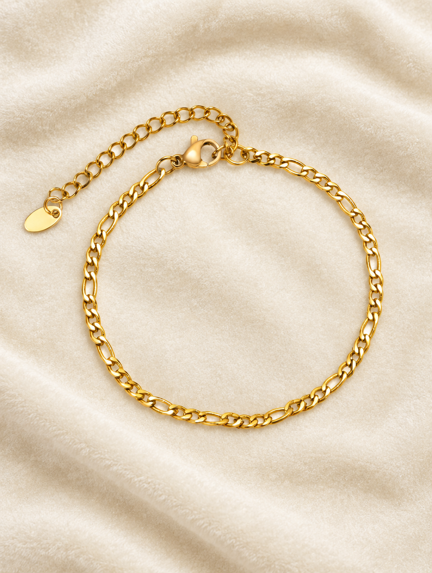 Gold figaro chain bracelet on cream velvet