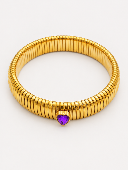 Gold wide ribbed stretch bracelet with a purple heart gem on a neutral background