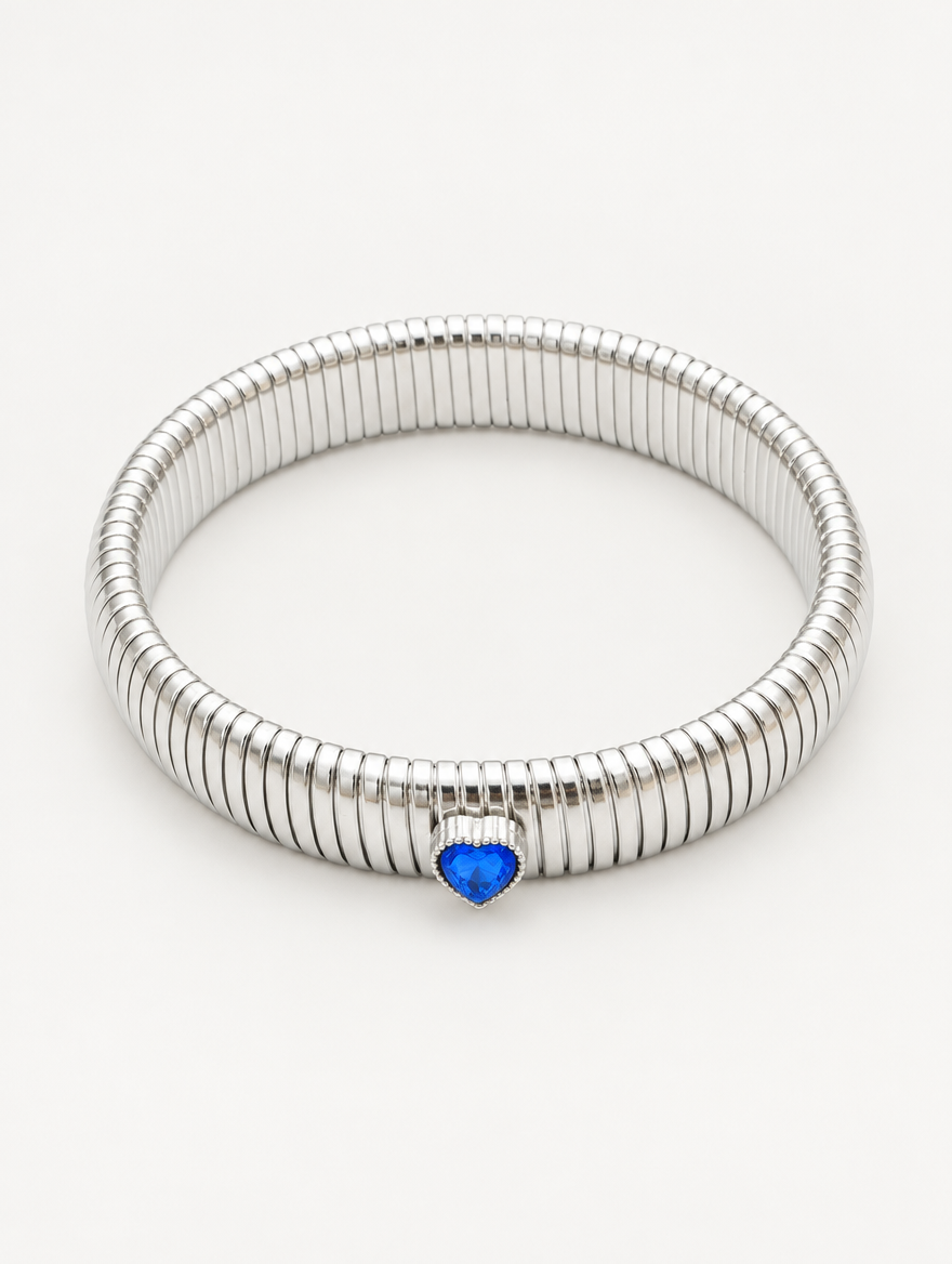 Silver wide ribbed stretch bracelet with a blue heart gem on a neutral background