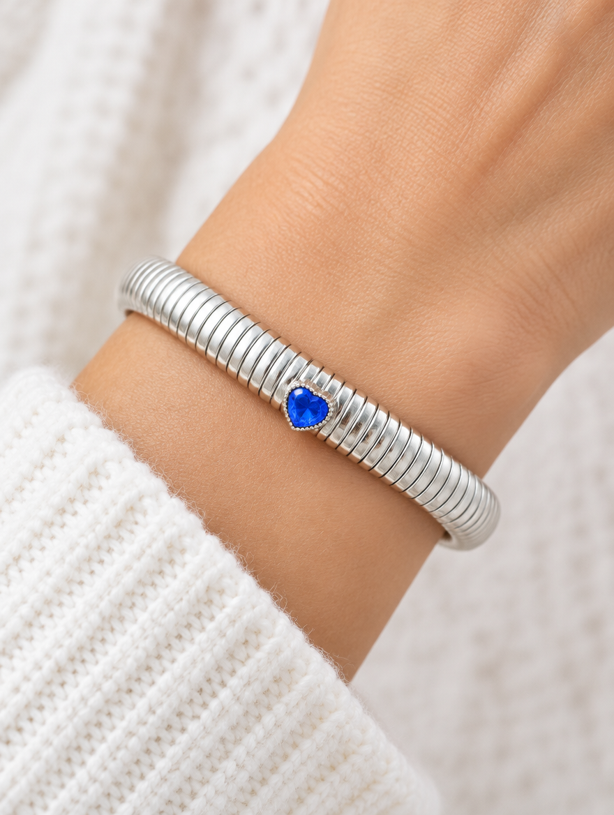 Woman wearing a silver stretch bracelet with a blue heart gem