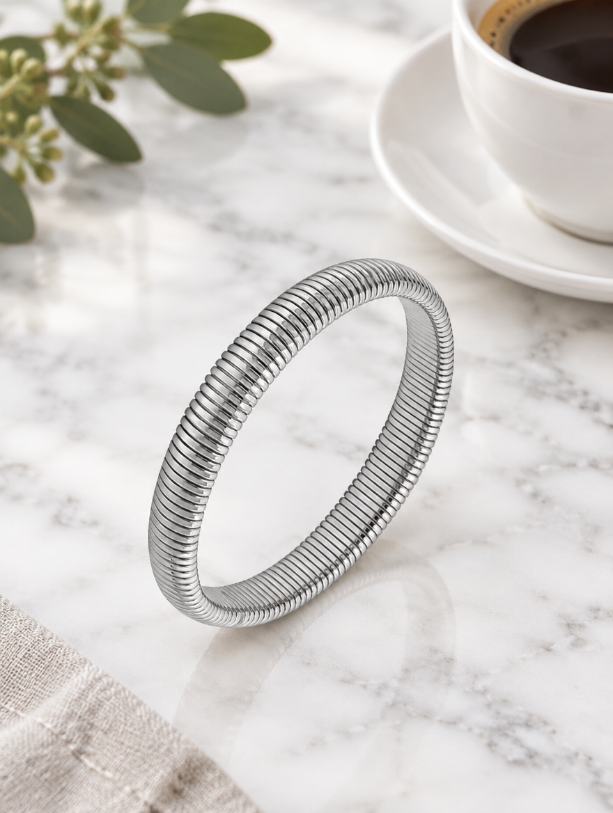 Silver ribbed stretch bracelet beside a coffee cup on marble