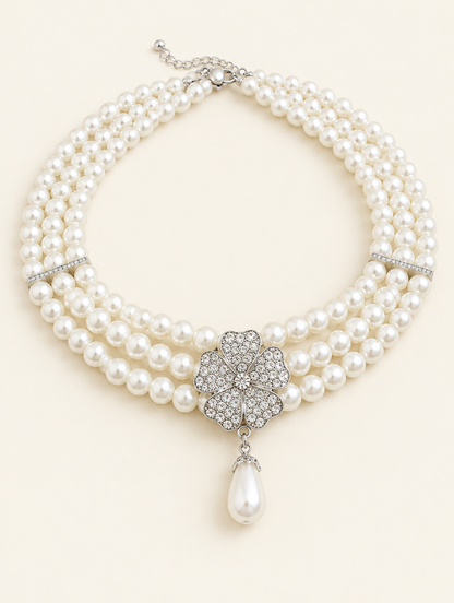 Three-strand pearl necklace with a rhinestone flower and teardrop pearl on a neutral background