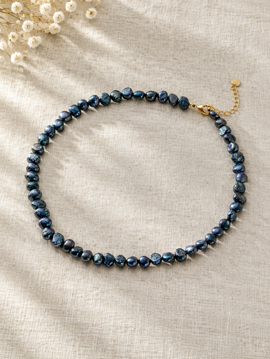 Black baroque pearl choker lying on soft linen