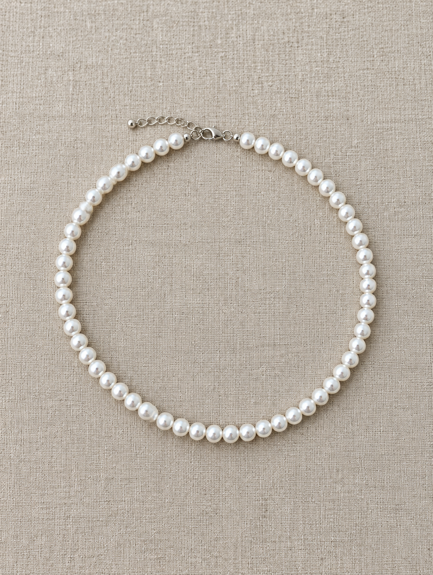 White pearl bead choker lying flat on soft linen