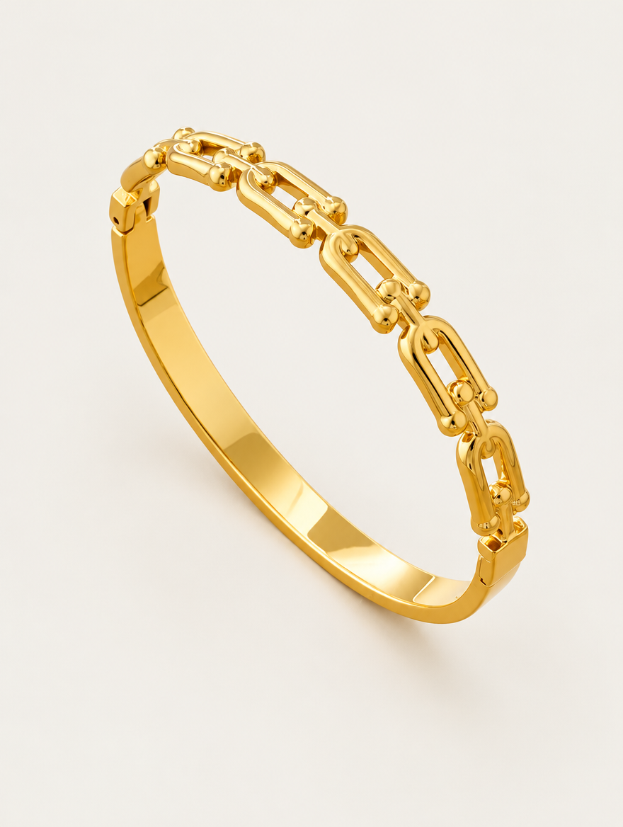 Gold hinged bangle with link cut-outs on a neutral background