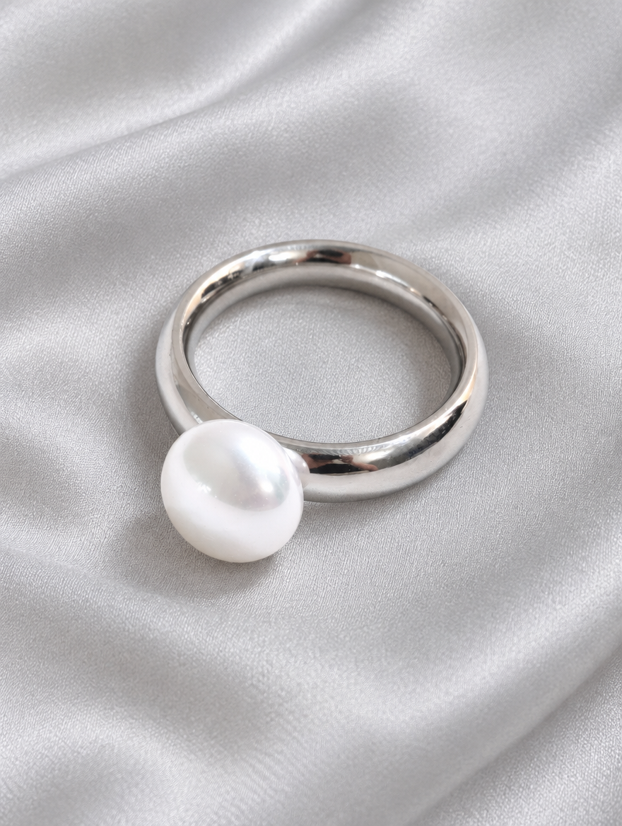 Silver pearl-effect bead ring resting on a soft textured surface