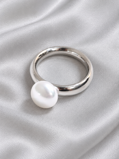 Silver pearl-effect bead ring resting on a soft textured surface