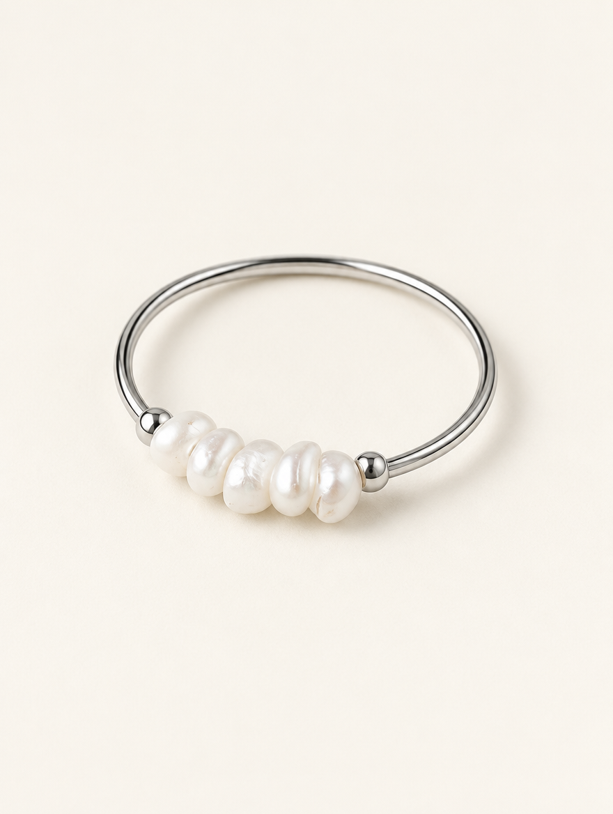 Silver four pearl band ring on a neutral background