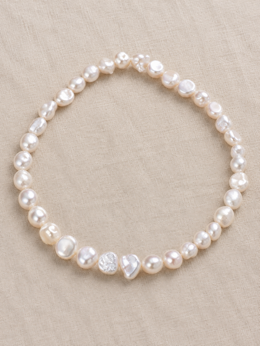 White baroque pearl choker lying on soft linen