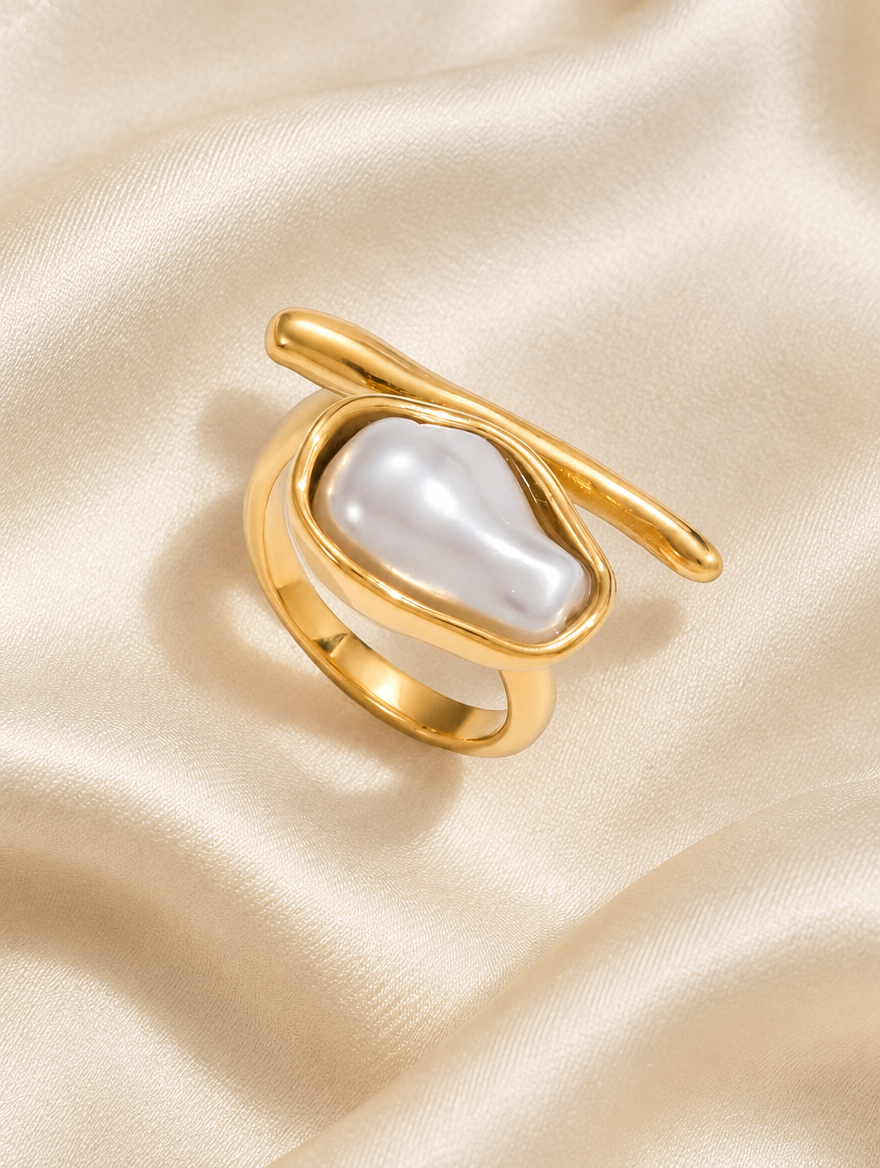 Gold baroque pearl wrap ring resting on a soft textured surface