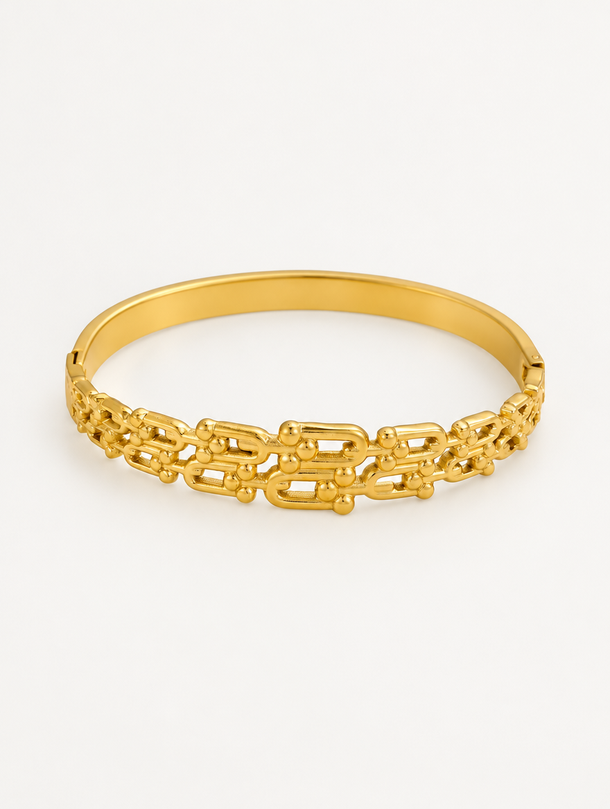 Gold hinged openwork bangle on a neutral background
