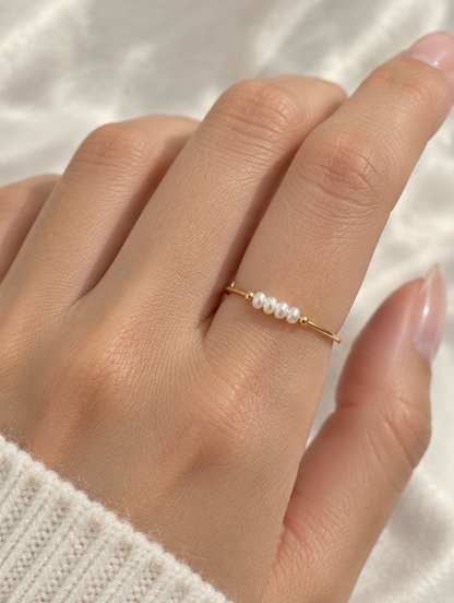 Woman wearing a gold four pearl band ring on her finger