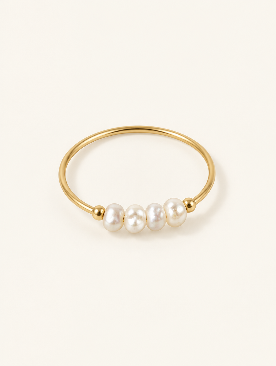 Gold four pearl band ring on a neutral background