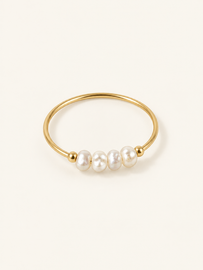 Gold four pearl band ring on a neutral background