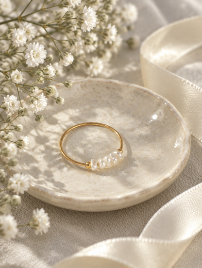 Gold four pearl band ring in a small dish with styling props