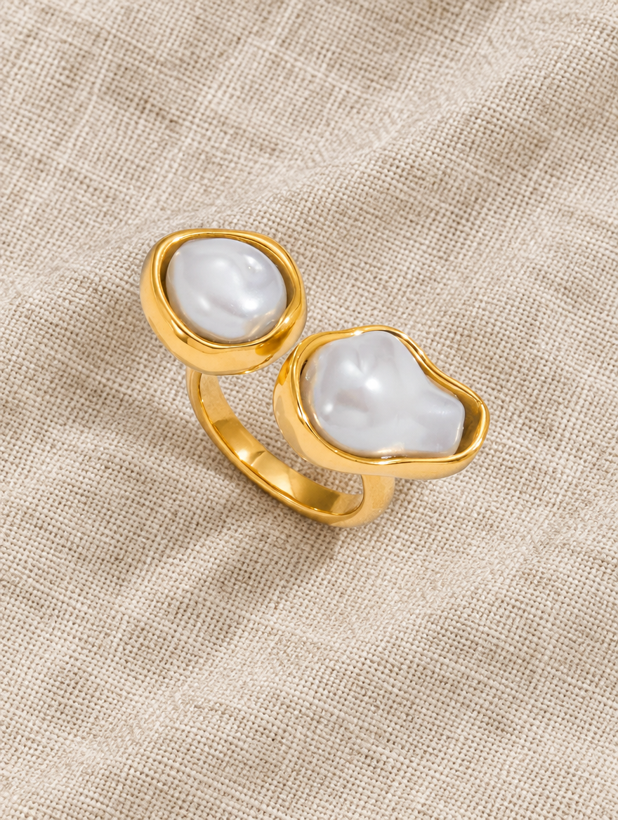 Gold double baroque pearl ring resting on a soft textured surface
