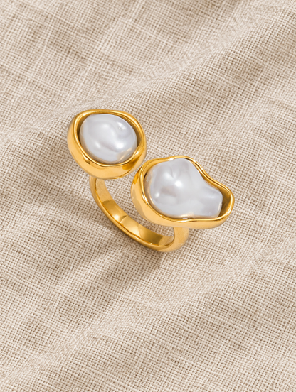 Gold double baroque pearl ring resting on a soft textured surface