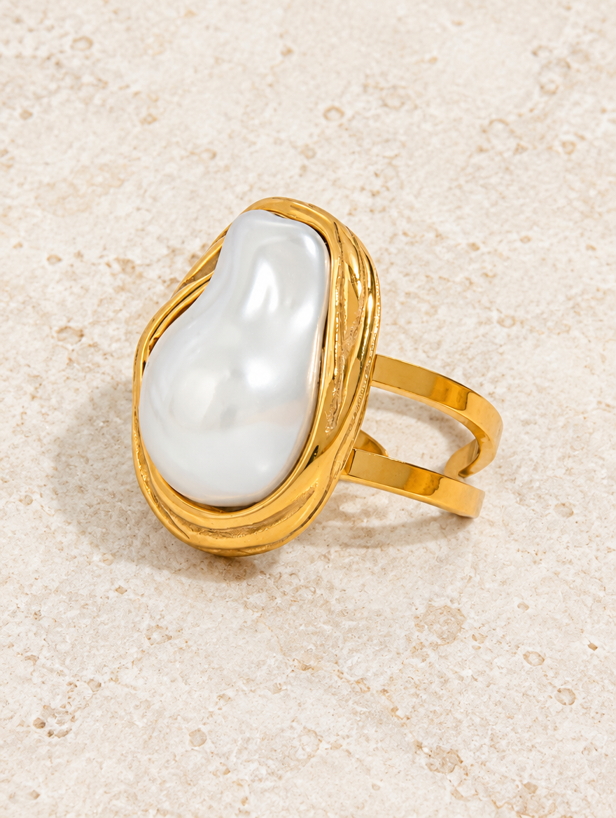 Gold oval baroque pearl ring resting on a soft textured surface