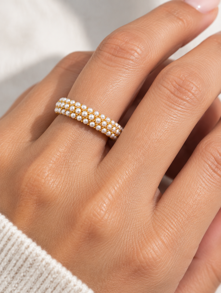 Woman wearing a gold pearl pavé band ring on her finger