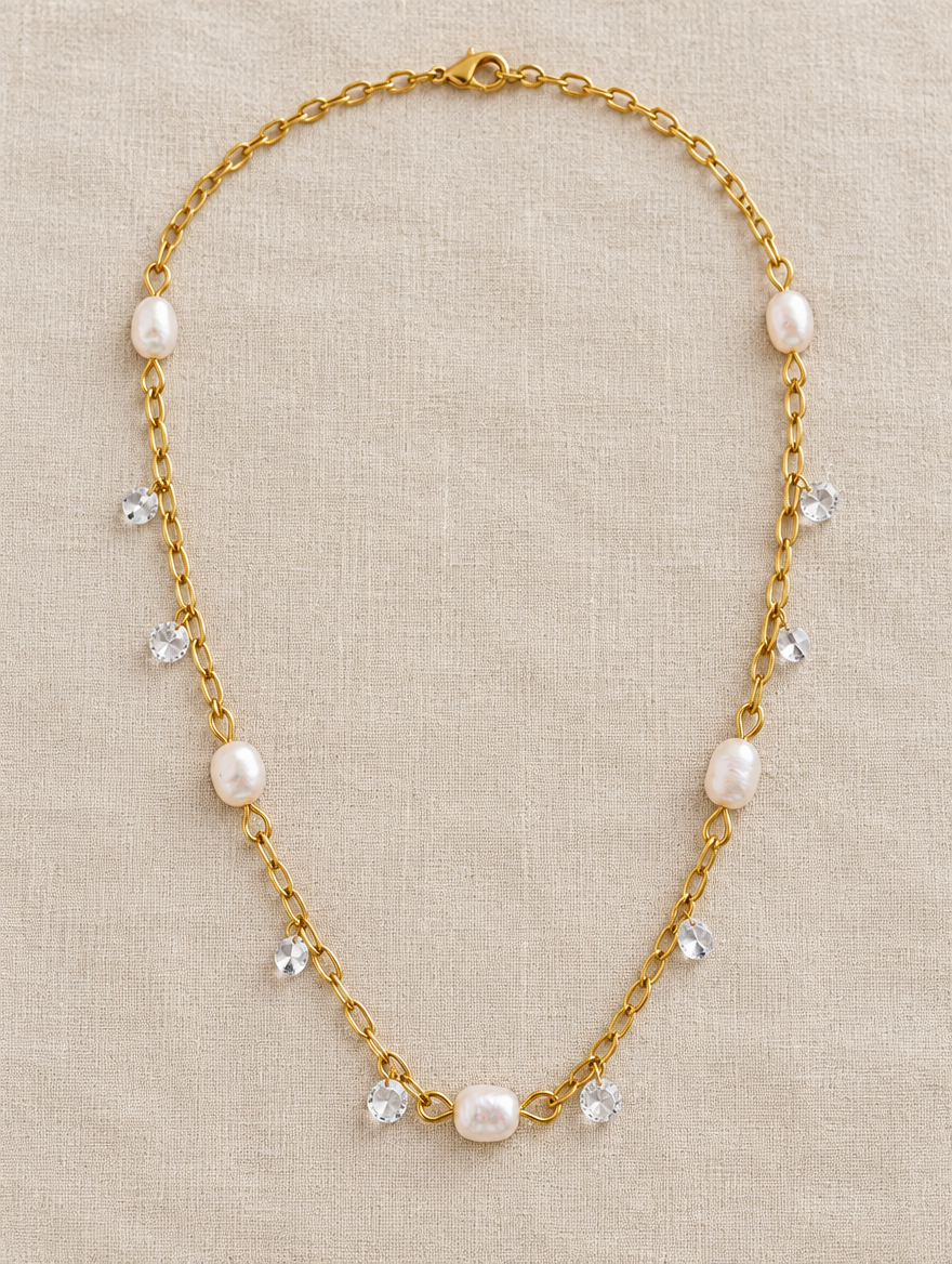 Gold pearl and zirconia necklace lying on linen