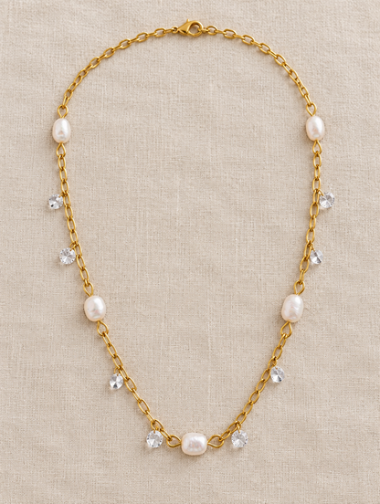 Gold pearl and zirconia necklace lying on linen