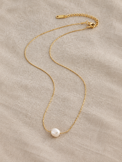 Gold pearl charm choker lying on linen