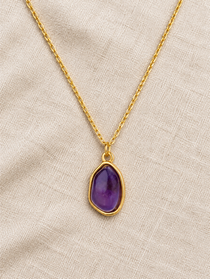 Purple stone pendant necklace lying on linen