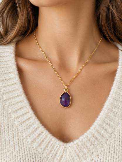 Woman wearing a gold-tone necklace with a purple oval stone pendant