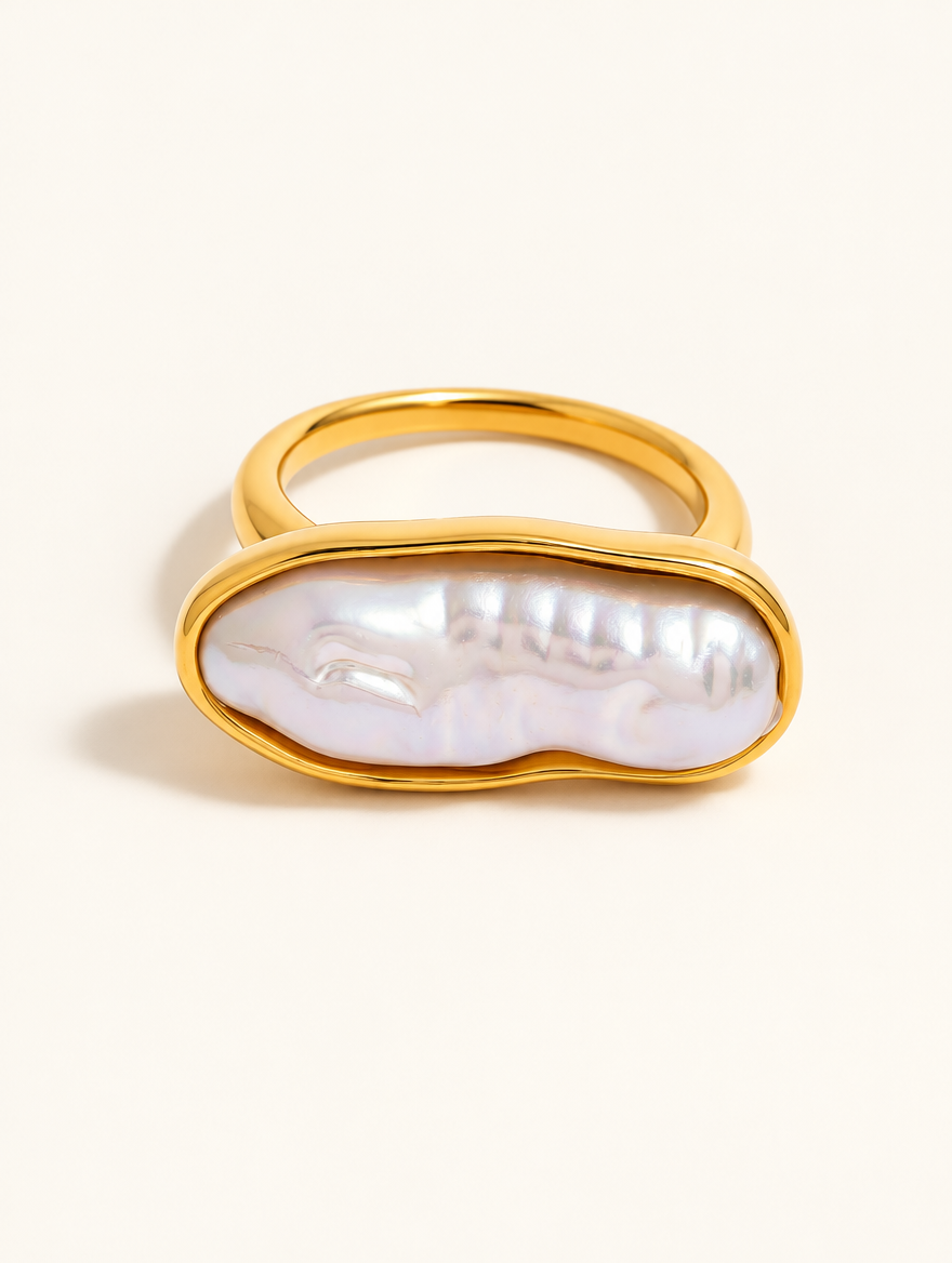 Gold long baroque pearl ring on a neutral background