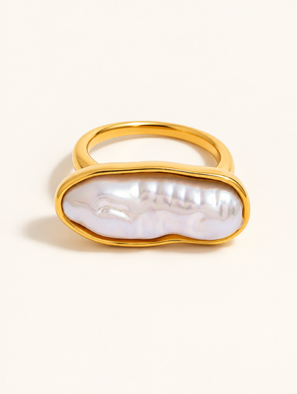 Gold long baroque pearl ring on a neutral background