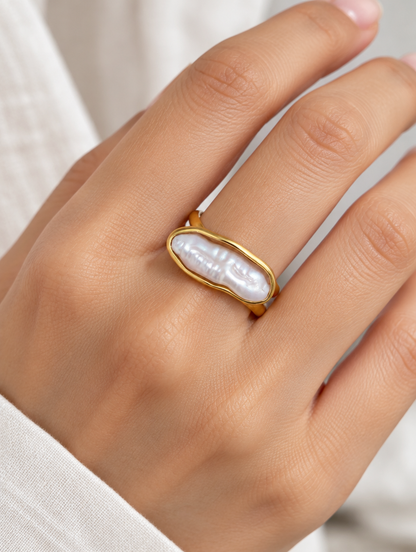 Woman wearing a gold long baroque pearl ring on her finger