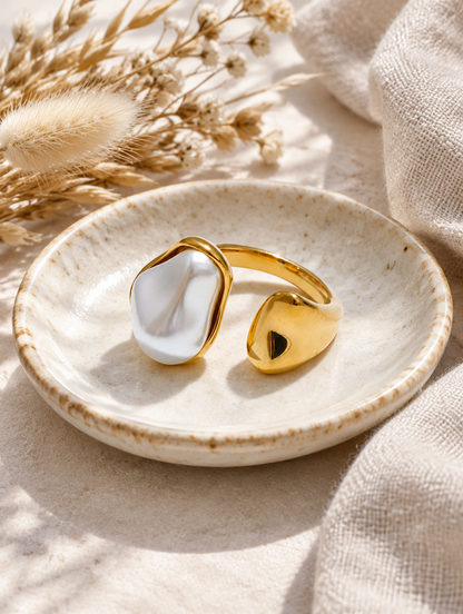 Gold baroque pearl teardrop ring in a small dish with styling props
