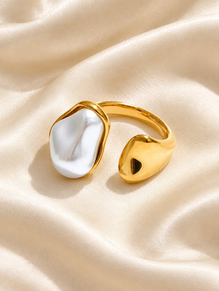 Gold baroque pearl teardrop ring resting on a soft textured surface