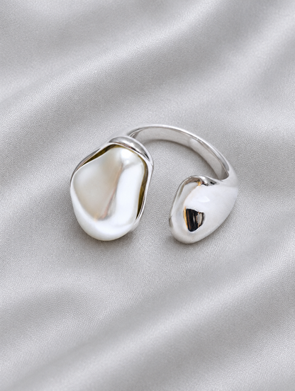 Silver baroque pearl teardrop ring resting on a soft textured surface