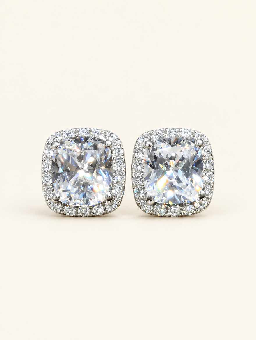 Pair of white halo cushion-cut cz stud earrings on a warm off-white background